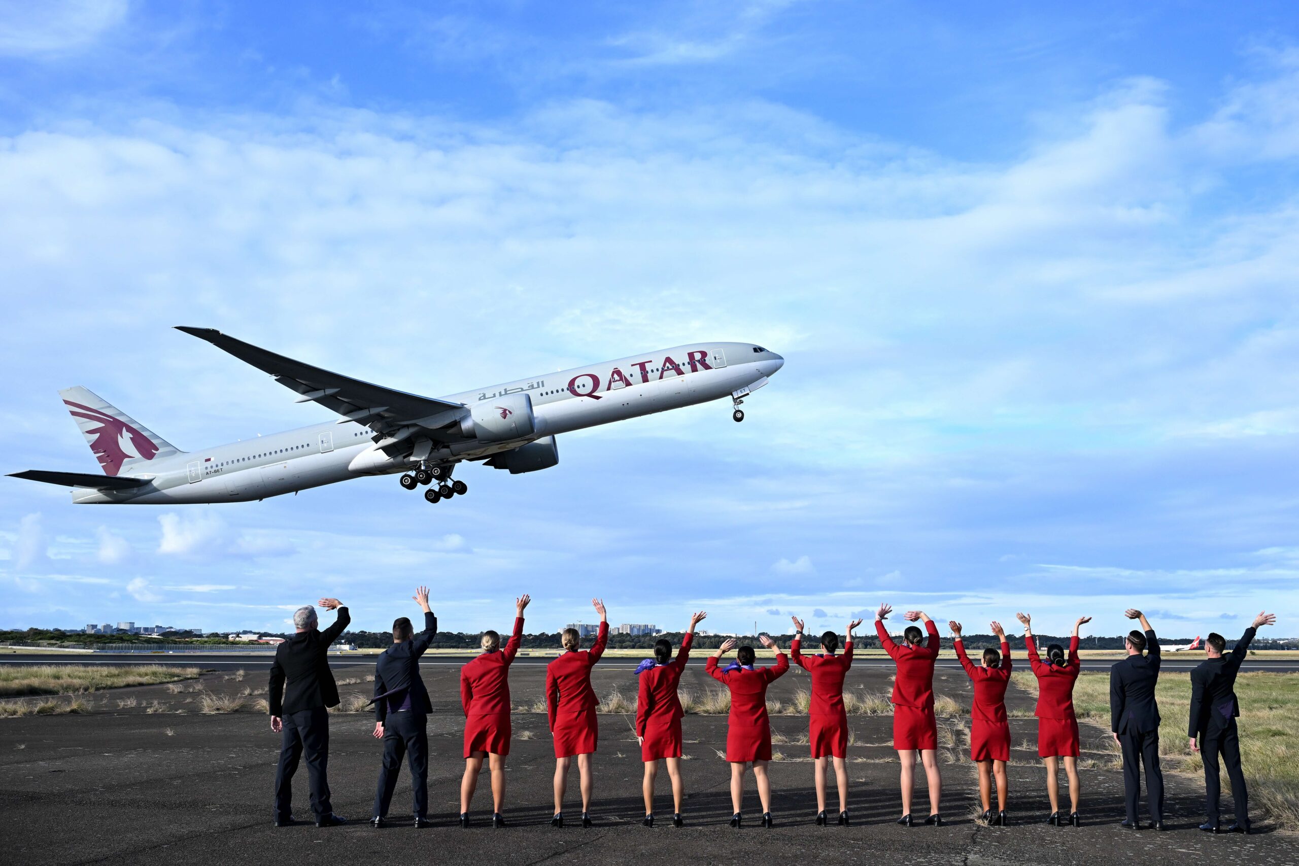 Virgin Australia cabin crew wave goodbye to the inaugural VA1 service from Sydney to Doha beside the runway at Sydney International Airport on Thursday. Virgin Australia is returning to international long-haul flights through an alliance with Qatar Airways five years after the pandemic forced it into administration and two years since Qatar Airways was initially blocked from expanding in Australia. (James D. Morgan/Getty Images for Virgin Australia)