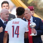 U.S. President Donald Trump presents Paris Saint-Germain's French midfielder Desire Doue with the Young Player Award after the FIFA Club World Cup 2025 final soccer match between England’s Chelsea and France’s PSG, which is majority owned by a subsidiary of the Qatar Investment Authority, at MetLife Stadium, New Jersey. Qatar Airways flight attendants carried the trophies and medals on stage for the ceremony. (AFP via Getty Images)