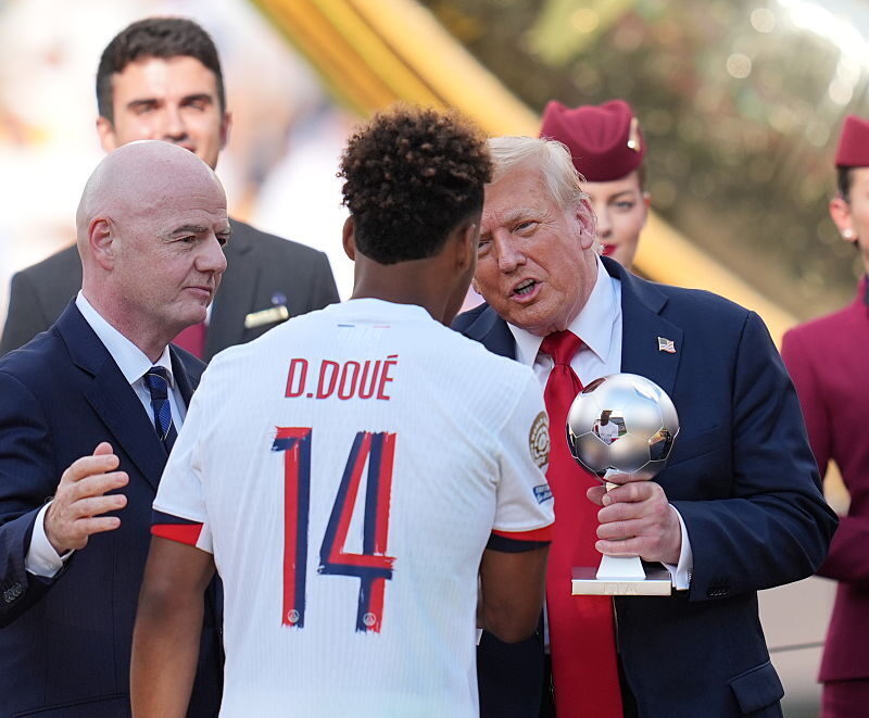 U.S. President Donald Trump presents Paris Saint-Germain's French midfielder Desire Doue with the Young Player Award after the FIFA Club World Cup 2025 final soccer match between England’s Chelsea and France’s PSG, which is majority owned by a subsidiary of the Qatar Investment Authority, at MetLife Stadium, New Jersey. Qatar Airways flight attendants carried the trophies and medals on stage for the ceremony. (AFP via Getty Images)